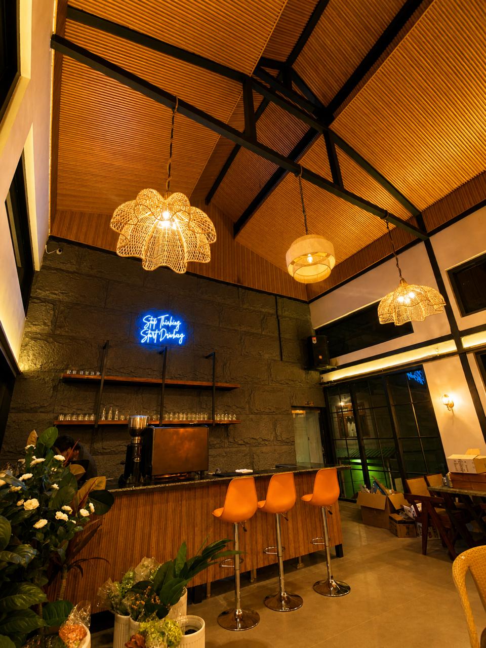 Terrace Café interior at Tiraya — neon sign, orange bar stools, warm rattan lighting, Tirthan Valley