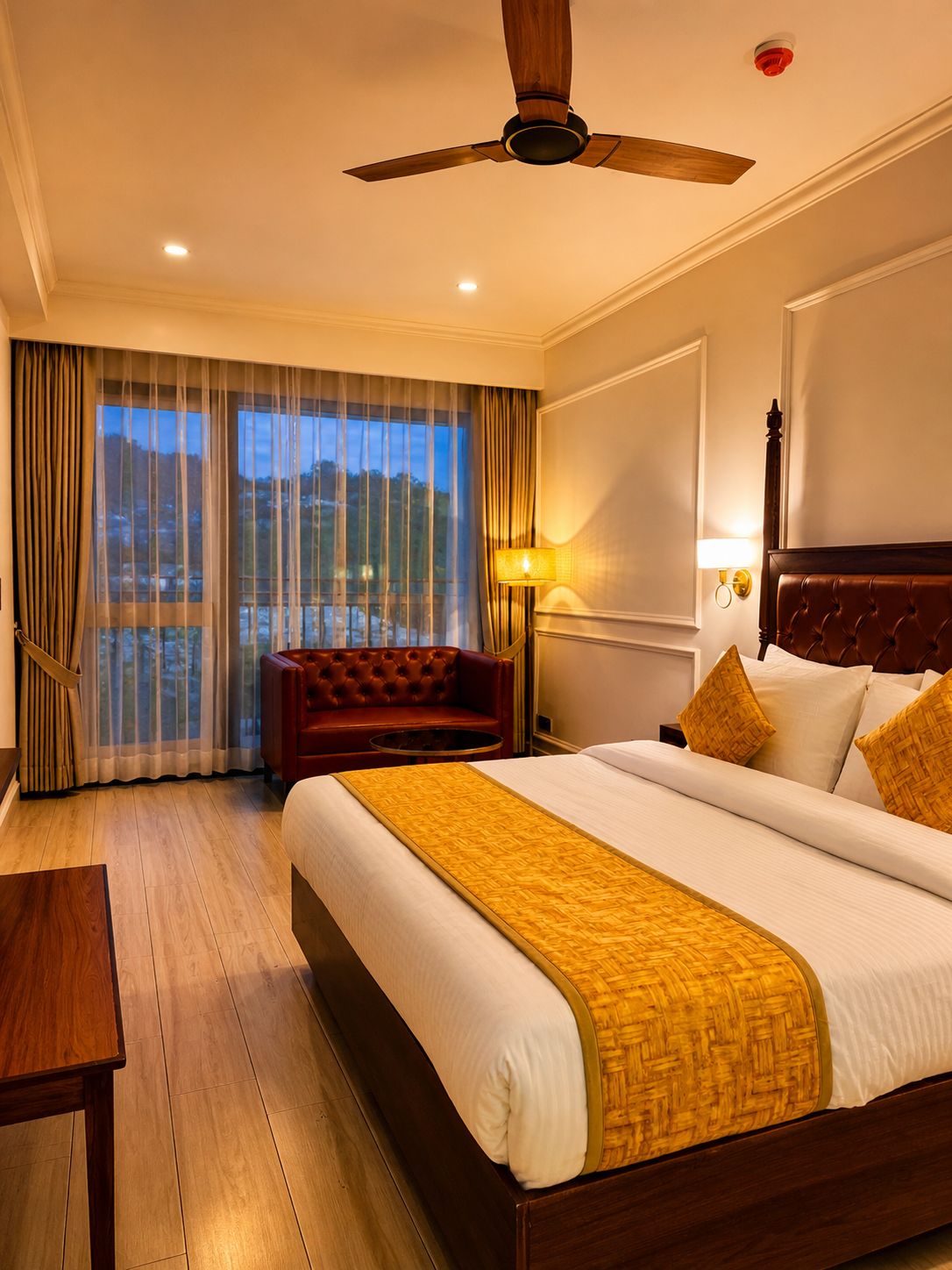 Premium Room at Tiraya — king bed with golden accents, leather sofa, private balcony overlooking Tirthan Valley